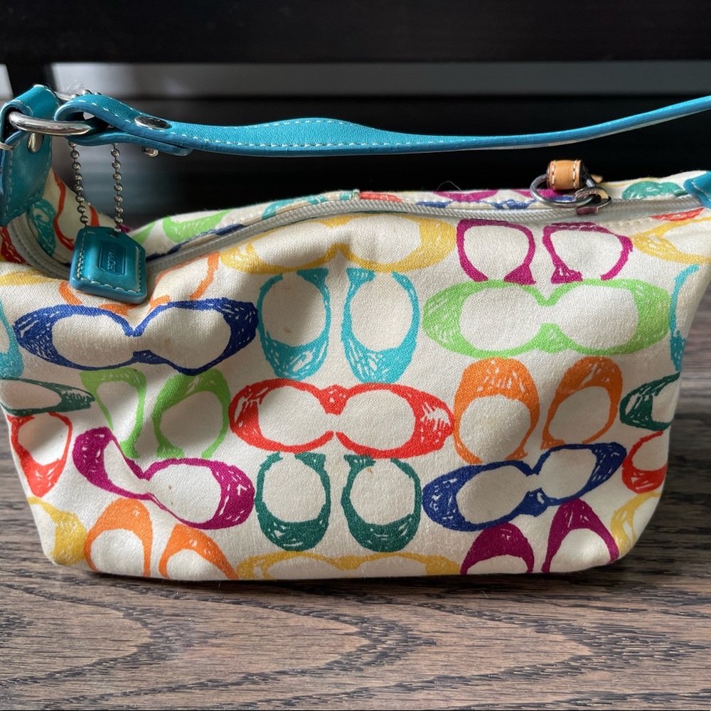 Clothe white Coach handbag with multicolored C pattern.